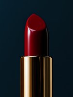 Classic red lipstick in golden metallic tube against dark background, dramatic studio lighting highlights luxurious cosmetic product detail and texture.