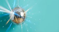 Shiny disco ball with sparkling light rays on turquoise background for party and nightclub entertainment events.
