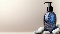 Elegant blue glass pump bottle with glitter effect on beige background with decorative spa stones, cosmetic packaging mockup for beauty products.