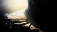 Ancient stone staircase leading upward toward bright light in dark cave or tunnel entrance creating dramatic contrast and spiritual atmosphere.