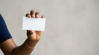 Hand holding blank white card for business messaging, advertising, or promotional content against neutral background.
