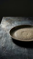 Rustic ceramic bowl with speckled glaze sitting on weathered dark surface, showcasing minimalist tableware design for culinary and home decor projects.