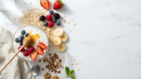 Healthy breakfast bowl with oats, fresh berries, banana slices and honey on white marble background. Nutritious morning meal ingredients for balanced diet.