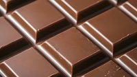 Dark chocolate bar segments in diagonal composition showing rich texture and glossy surface for food photography and confectionery advertising.