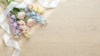 Delicate pastel flower bouquet with white ribbon on wooden background. Spring wedding arrangement with roses and blue blooms for romantic celebrations.