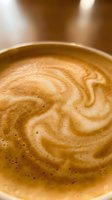 Overhead view of latte with decorative latte art swirl pattern in ceramic cup, showcasing creamy espresso and steamed milk foam for coffee shop, café, and beverage concepts.