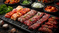 Raw marinated meat cuts arranged on black grill plate with fresh herbs and side dishes in bowls. Korean BBQ style preparation with various marinades and garnishes.