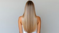 Young woman with long straight blonde ombre hair shown from behind on light background. Professional hairstyle demonstrates smooth, healthy hair texture and modern coloring technique.