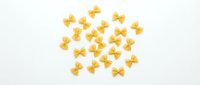 Farfalle pasta scattered on white background, isolated food ingredient for cooking and culinary design projects.