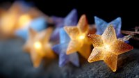 Glowing star-shaped lights create magical holiday atmosphere with warm golden illumination and soft blue bokeh effect against dark background.