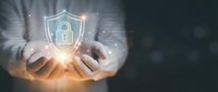 Businessman hands protecting glowing digital security shield with padlock icon representing cybersecurity data protection and privacy safeguarding technology.
