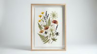 Pressed wildflower botanical art in wooden frame featuring dried ferns, lavender, daisies and autumn leaves for home decor and wall art projects.
