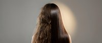 Woman with long brown hair showing before and after hair treatment results on neutral background for beauty and haircare concepts.