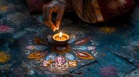 Female hand lighting traditional oil lamp on colorful rangoli pattern during Diwali festival celebration in India.