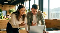 Young woman and man of mixed ethnicity collaborating at laptop in modern office with plants and city views, suitable for business, teamwork, startup, and corporate communication projects.