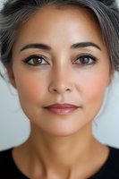 Close up portrait of mature Asian woman with silver gray hair and natural makeup showing confidence and grace against light background. Professional beauty concept.