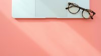Open notebook with blank pages and tortoiseshell eyeglasses on pink background, flat lay composition for education, business, and creative projects.