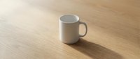White ceramic mug on wooden surface with natural lighting, suitable for beverage branding, product mockups, and cafe marketing materials.