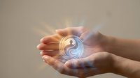 Two hands holding glowing yin yang symbol with light rays, representing balance, harmony, spirituality, and wellness concepts for meditation and alternative healing practices.
