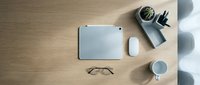 Minimalist workspace flat lay with tablet, mouse, glasses, coffee cup and plant on wooden desk, top view, modern office setup.