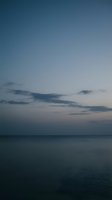 Serene twilight seascape with calm ocean waters and dramatic cloud formations across the horizon during dusk or dawn. Peaceful coastal scene.