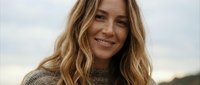 Portrait of smiling blonde woman in cozy sweater during golden hour outdoors. Natural beauty and warmth captured in soft lighting for lifestyle content.
