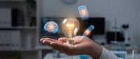 Professional hand holding glowing lightbulb with floating digital icons representing innovation, creativity and technology in modern office environment.