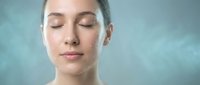 Young Caucasian woman with closed eyes and serene expression enjoying spa treatment with steam or mist for skincare and wellness relaxation.