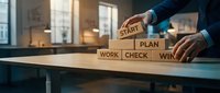 Business professional arranging wooden blocks spelling START PLAN WORK CHECK WIN on office desk, representing strategic planning and success methodology.