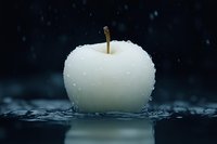 Fresh white apple covered in water droplets on dark background with rain splashes, showcasing natural purity and organic freshness.