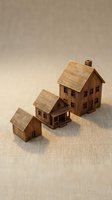 Three miniature wooden house models of different sizes arranged on a linen surface, symbolizing real estate growth and property investment concepts.