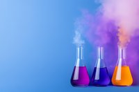 Laboratory glass flasks with colorful liquids and rising smoke against blue background, creating vibrant chemistry experiment atmosphere with purple and orange solutions.