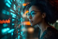 Young African American woman with natural curly hair and glasses looking at futuristic digital interface display with glowing cyan data visualization elements.