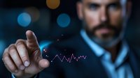 Businessman pointing at glowing financial chart hologram in dark office. Digital technology visualization shows market data analysis and trading concept.