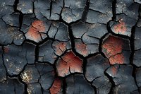 Cracked weathered paint surface with rust showing through dark peeling layers creating abstract textural pattern for backgrounds and design projects.
