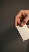 Hand holding a blank white business card against dark background, mockup for branding, networking, and corporate identity design concepts.