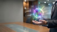 Businessman in dark suit holding glowing digital globe with holographic data analytics, charts and network connections floating above palm at wooden desk.
