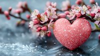 Pink glittery heart decoration with blooming cherry blossoms against dark background, romantic spring composition for Valentine's Day and love themes.