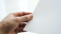 Hand turning white paper page corner on clean background for reading and document concepts.