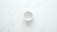 Empty white ceramic cup on marble surface, overhead view, minimalist design for beverage, kitchen, and lifestyle projects.