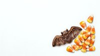 Chocolate bat with candy corn isolated on white background, ready for Halloween designs, clipart, and seasonal marketing materials.
