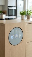 Modern smart kitchen island with circular touchscreen display showing home automation icons in contemporary wooden interior design.