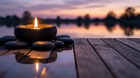 Zen stone candle burning on wooden dock at sunset lake creating peaceful meditation atmosphere with warm golden light reflecting on calm water surface.