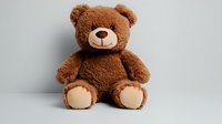 Brown plush teddy bear with beige paws sitting against light background, soft fluffy stuffed animal toy for children and holiday gifts.