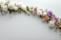 Curved floral arrangement with white carnations, pink roses, and purple dahlia on light background. Fresh spring flowers create elegant arch composition.