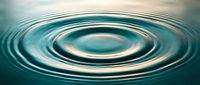 Water ripples creating concentric circles on calm turquoise surface with soft lighting and peaceful atmosphere for wellness and meditation concepts.