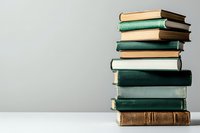 Stack of vintage hardcover books in green and brown colors on white table against neutral gray background, creating minimalist academic composition.