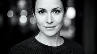 Professional black and white portrait of confident middle-aged Caucasian businesswoman with bokeh city lights background for corporate branding materials.