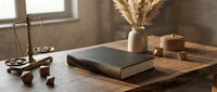 Law book and brass justice scales on rustic wooden desk with dried pampas grass, warm moody lighting for legal and education concepts.