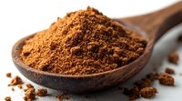 Ground cinnamon powder in wooden spoon macro close up view, aromatic spice ingredient for baking and cooking on blurred background.